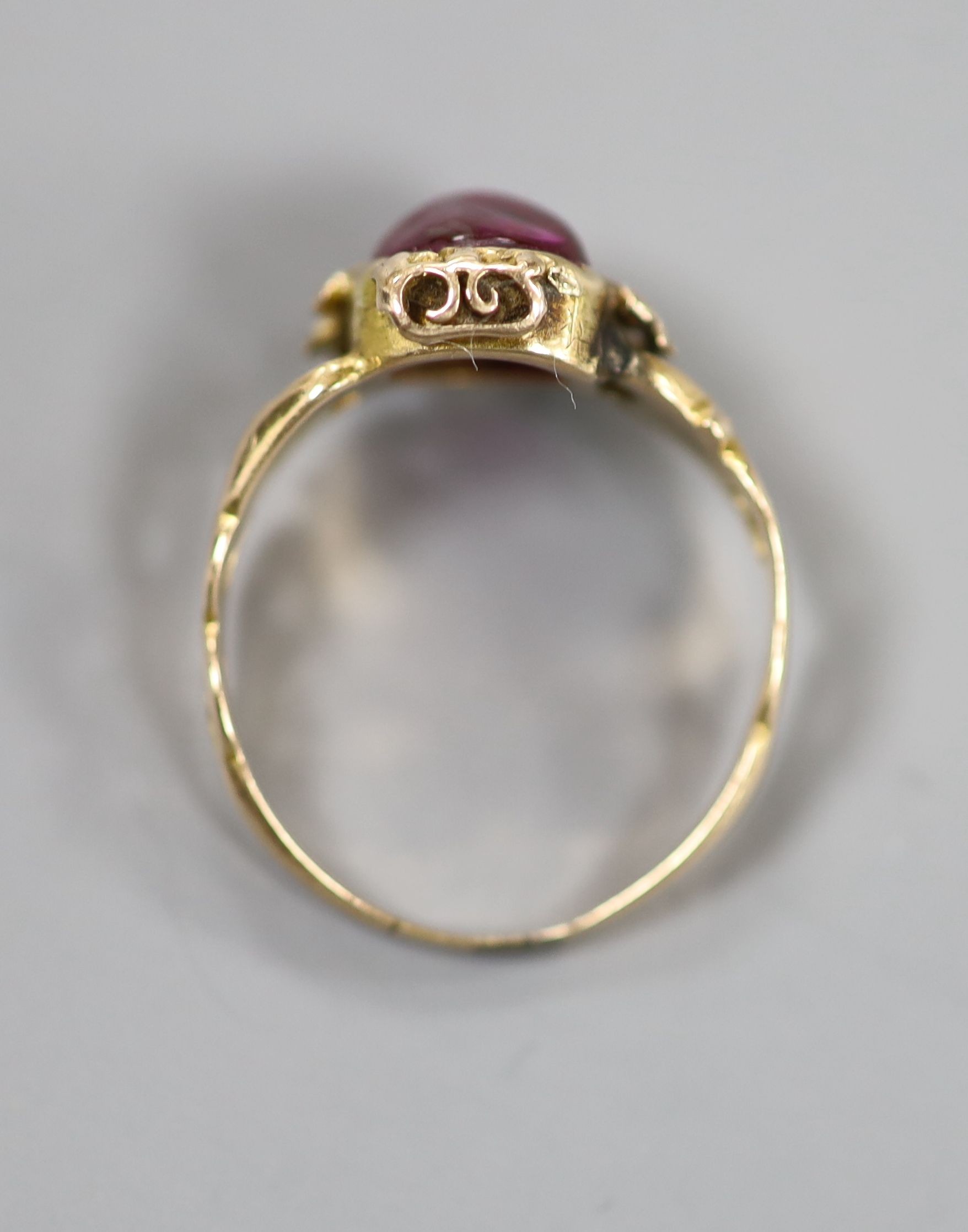 An early 20th century yellow metal and red cabochon set oval ring, size K/L, gross weight 2.4 grams.